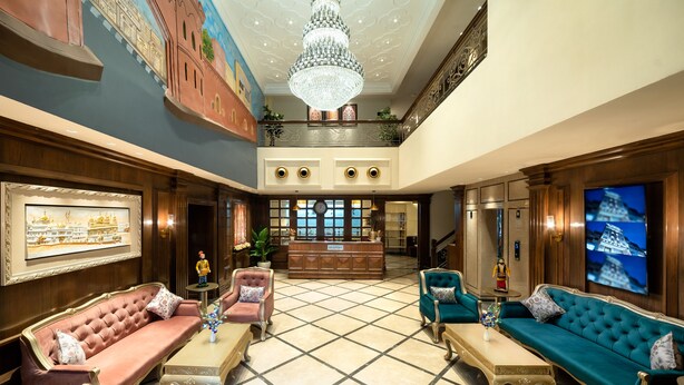 A luxurious lobby with a grand chandelier, plush seating, a reception desk, and a large TV screen. - Country Inn Hall Of Heritage Amritsar (Amritsar)