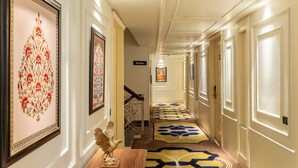 A hallway with framed artwork, a staircase, and patterned carpets. - Country Inn Hall Of Heritage Amritsar (Amritsar)