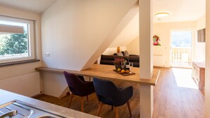 Una cucina moderna con un piano di lavoro in legno, due sedie e un'area pranzo con tavolo apparecchiato per due persone.