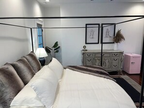 Un dormitorio con una cama con dosel, un aparador y obras de arte enmarcadas en la pared.