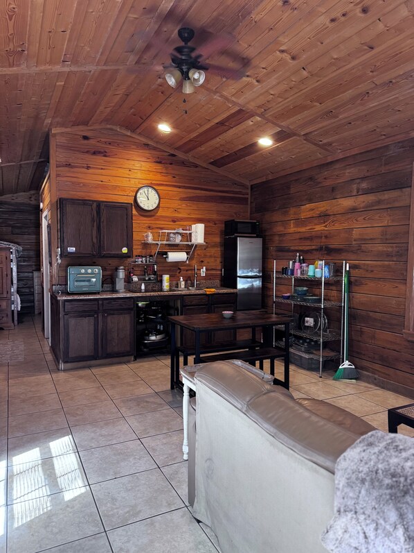 Enjoy cooking and dining in this well-equipped kitchen and living area, featuring a stove, microwave, and refrigerator, with a dining table and comfortable seating.