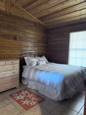 Cozy bedroom with a neatly made bed, wooden nightstand, and a red star-patterned rug.