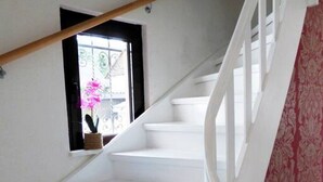 A white staircase with a wooden handrail and a red patterned carpet on the right.