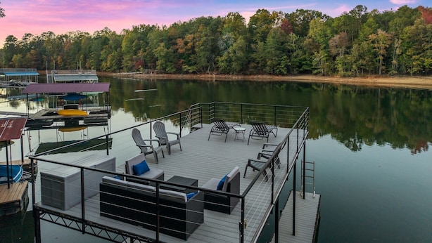 A dock with outdoor seating and a view of a lake surrounded by trees. - Private Dock | Hot Tub | Kayaks | GameRoom | EV (Dawsonville)