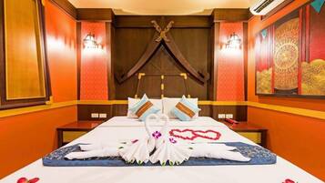 A hotel room with a large bed, decorative pillows, a wall-mounted light fixture, and a decorative wall piece.