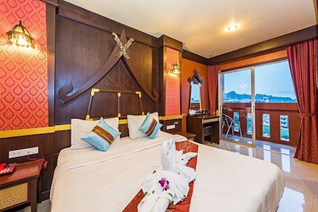 A hotel room with a large bed, a desk, and a balcony with a view.