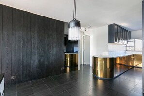 Una cocina moderna con paneles de madera oscura, una isla central y una lámpara colgante.