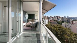 Ein Balkon mit Stadtblick, eine Schiebetür und eine Sitzecke mit Tisch und Stühlen.