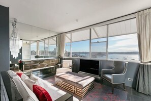 A modern living room with a large window, a sofa, a coffee table, and a television. - Luxury 1 Bedroom Apt with Harbour Views & Parking (Sydney)