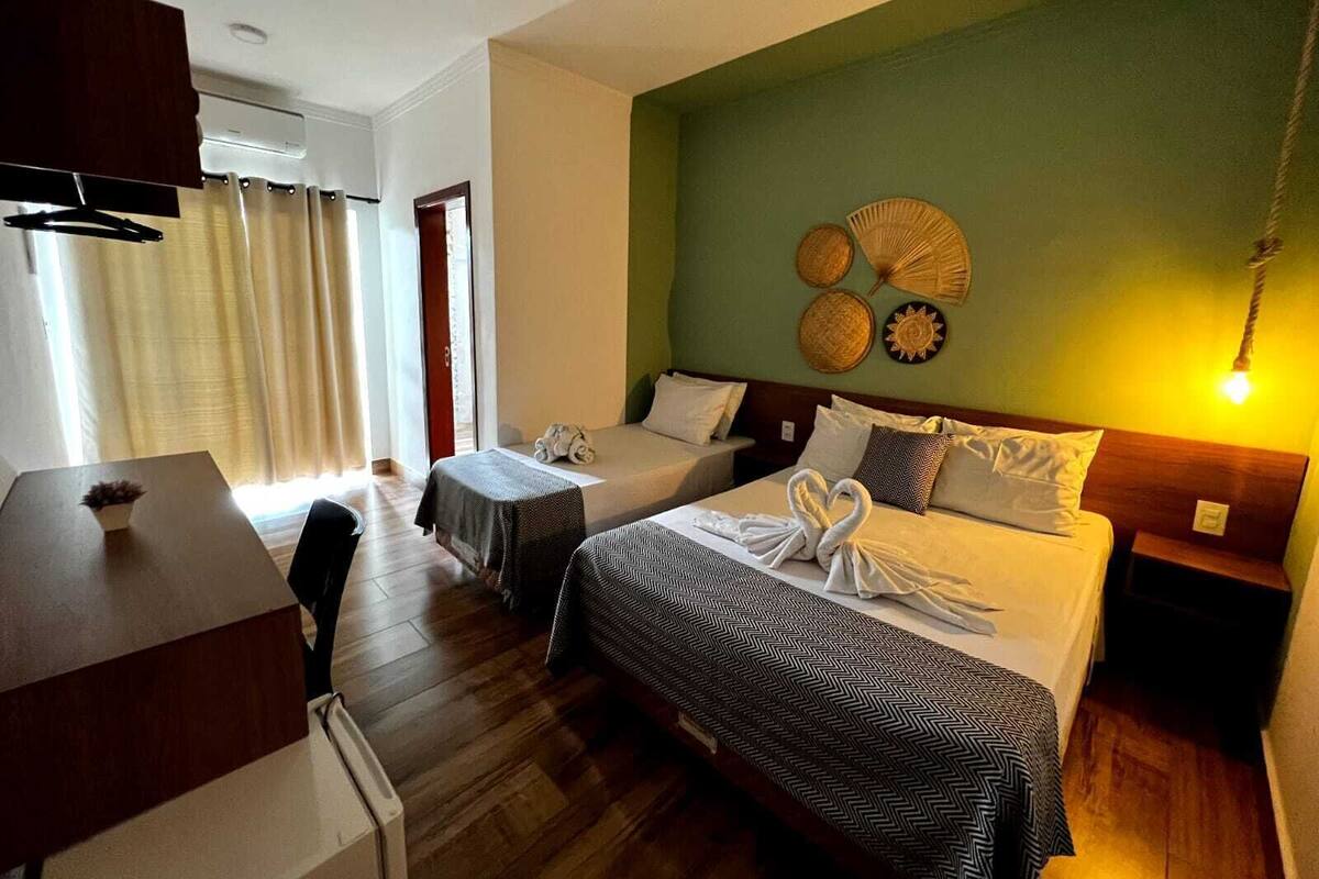 Habitación de hotel con dos camas, un escritorio y una silla. Se observan adornos en la pared y una lámpara en la mesita de noche.