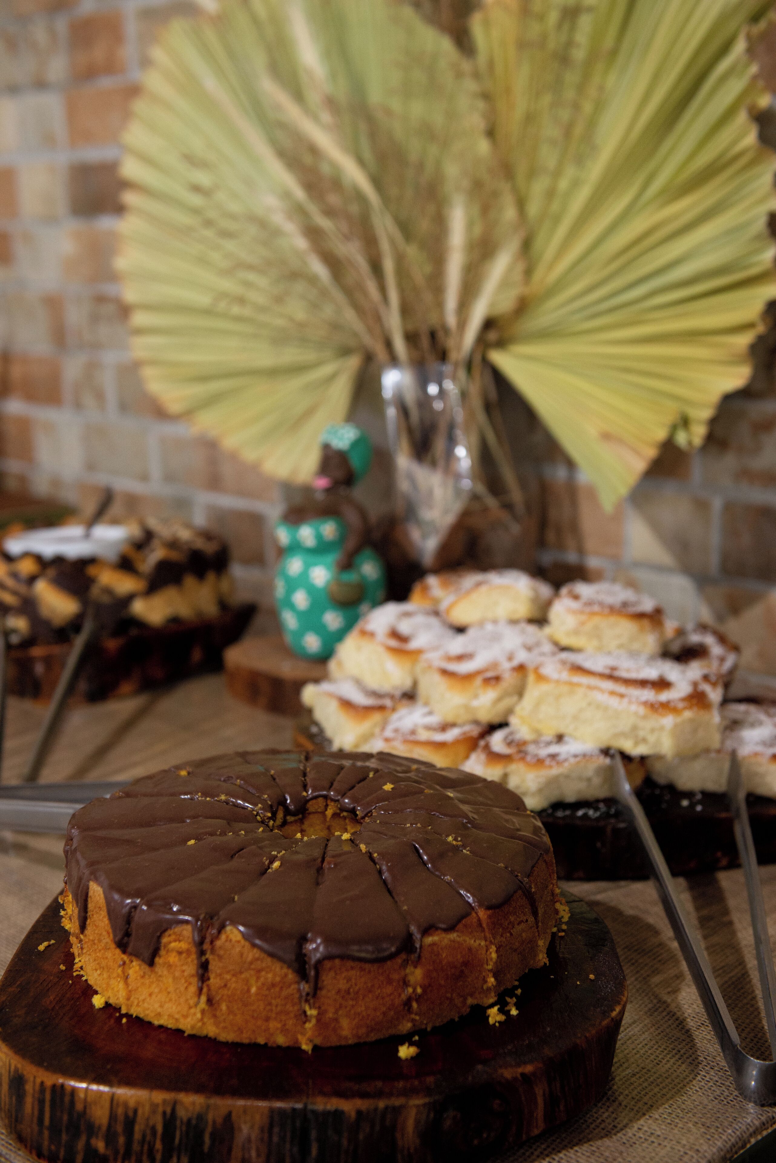 A variety of desserts on a wooden board, including a chocolate cake with a glossy finish.