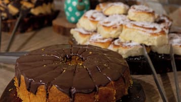 A variety of desserts on a wooden board, including a chocolate cake with a glossy finish.