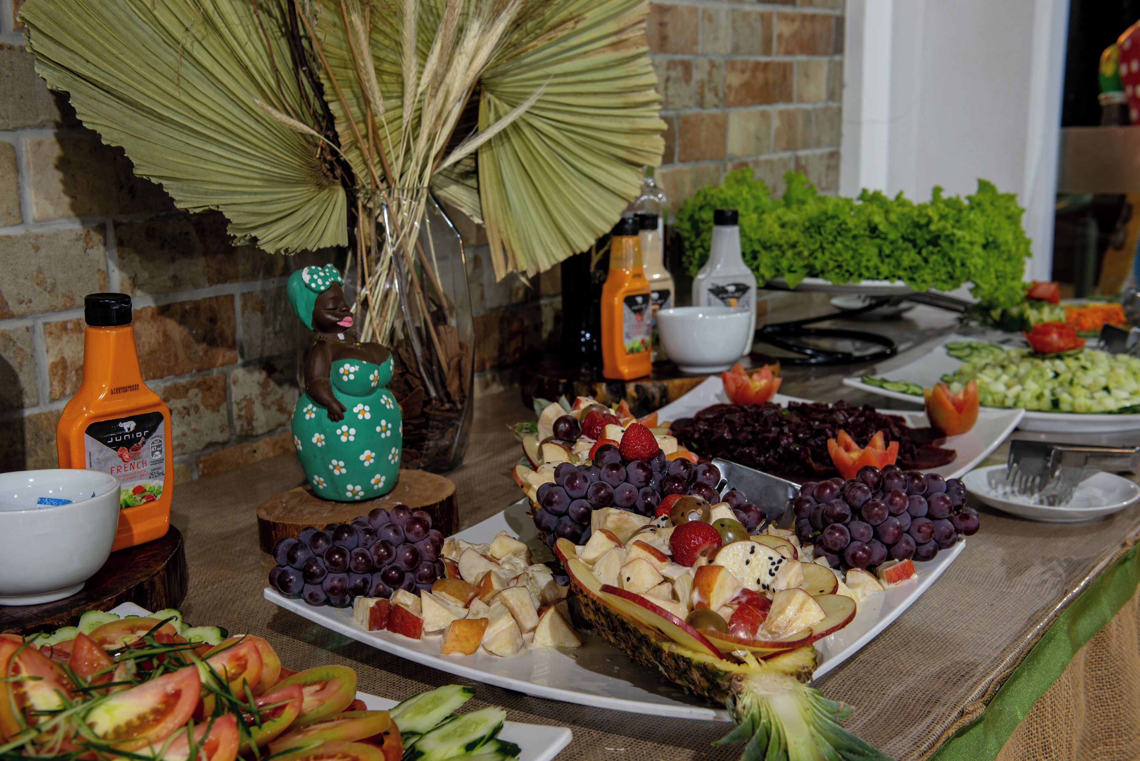 Uma mesa de buffet com diversas frutas, legumes e acompanhamentos.