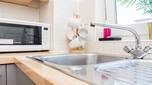 A modern kitchen with a microwave, a sink, and a mug rack. - Bayview Apartments (Southampton)
