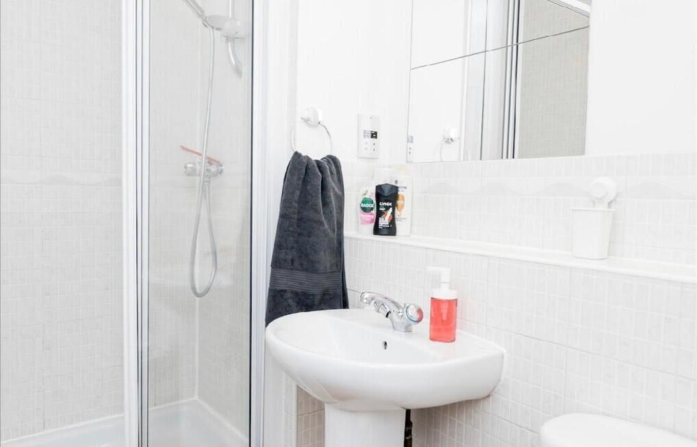 A modern bathroom with a glass shower enclosure, a white sink, and a mirror above the sink.