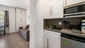 A compact kitchen with white cabinets, a microwave, a dishwasher, and a small countertop area. - Beach Bae, Bright Studio, Steps to the Ocean (Miami Beach)