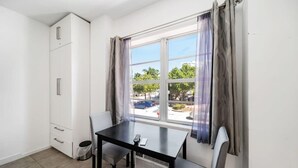 A small room with a window, a table, two chairs, a cabinet, and a radiator. - Beach Bae, Bright Studio, Steps to the Ocean (Miami Beach)