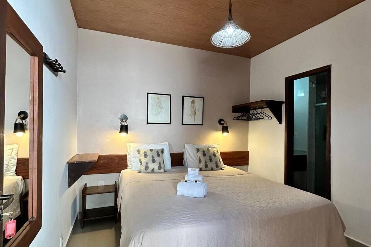 Ein Hotelzimmer mit einem großen Bett, einer Holzbalkendecke, einer Pendelleuchte und einem kleinen Nachttisch.