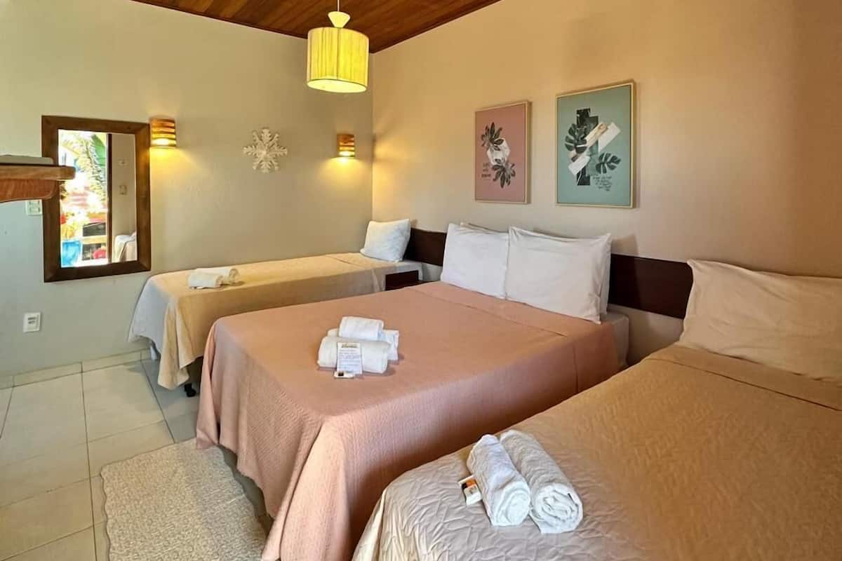 Ein Hotelzimmer mit zwei Betten, einer Holzbalkendecke, einem kleinen Teppich und Wandleuchten.