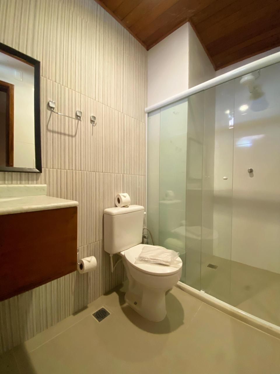 A modern bathroom with a toilet, a glass shower enclosure, and a wooden vanity.
