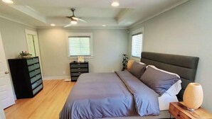 Ein Schlafzimmer mit Bett, Schminktisch, Nachttisch und Deckenventilator.