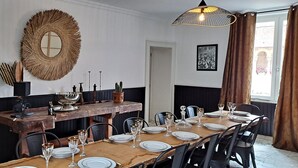 Een eethoek met een lange tafel gedekt voor een maaltijd, een decoratieve spiegel en een hanglamp.