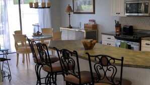 A spacious kitchen with a central island, wooden chairs, and a dining table. - Waterfront Spanish Villa with private pool and lake views - 5 mins from beach! (Bonita Springs)