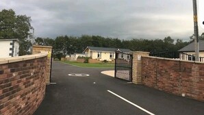 Un quartiere residenziale recintato, con muri in mattoni e una strada asfaltata che porta alle case.