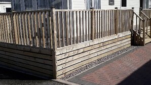 Un’abitazione mobile con una veranda in legno e un vialetto in mattoni che conduce all'ingresso.