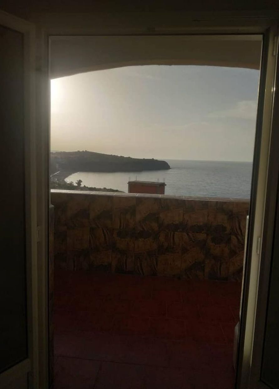 Vista da un balcone con un muro in pietra e una porta che dà su una stanza.