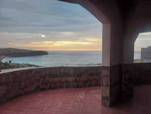 Un balcon avec vue sur la mer et sur le coucher du soleil.