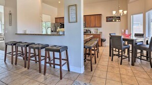 Une cuisine moderne avec un coin bar, des tabourets en bois et une table à manger avec des chaises.