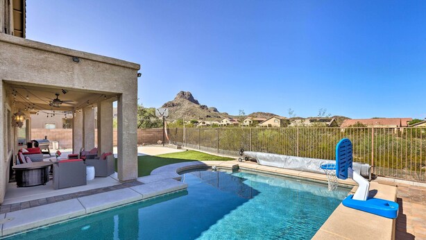 Une piscine avec un panier de basketball, un espace extérieur aménagé pour s’asseoir et une vue sur une montagne.