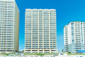 A multi-story hotel with a uniform exterior, balconies, and a clear blue sky.