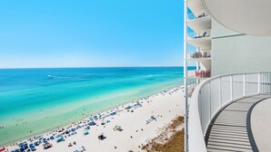 Un hôtel situé en bord de mer, doté d’un balcon incurvé qui offre une vue sur une plage de sable fin et des eaux turquoise.