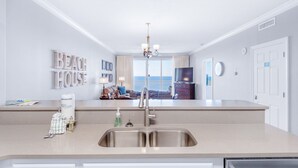 Une cuisine moderne dotée d’un îlot central, d’un évier et donnant sur l’espace de vie.