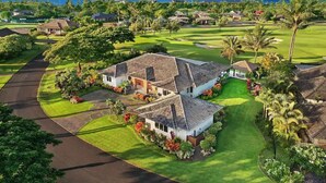 A golf course with houses, palm trees, and a view of the ocean.