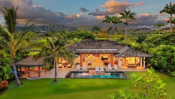 A house with a pool, outdoor seating, and a thatched-roof structure.
