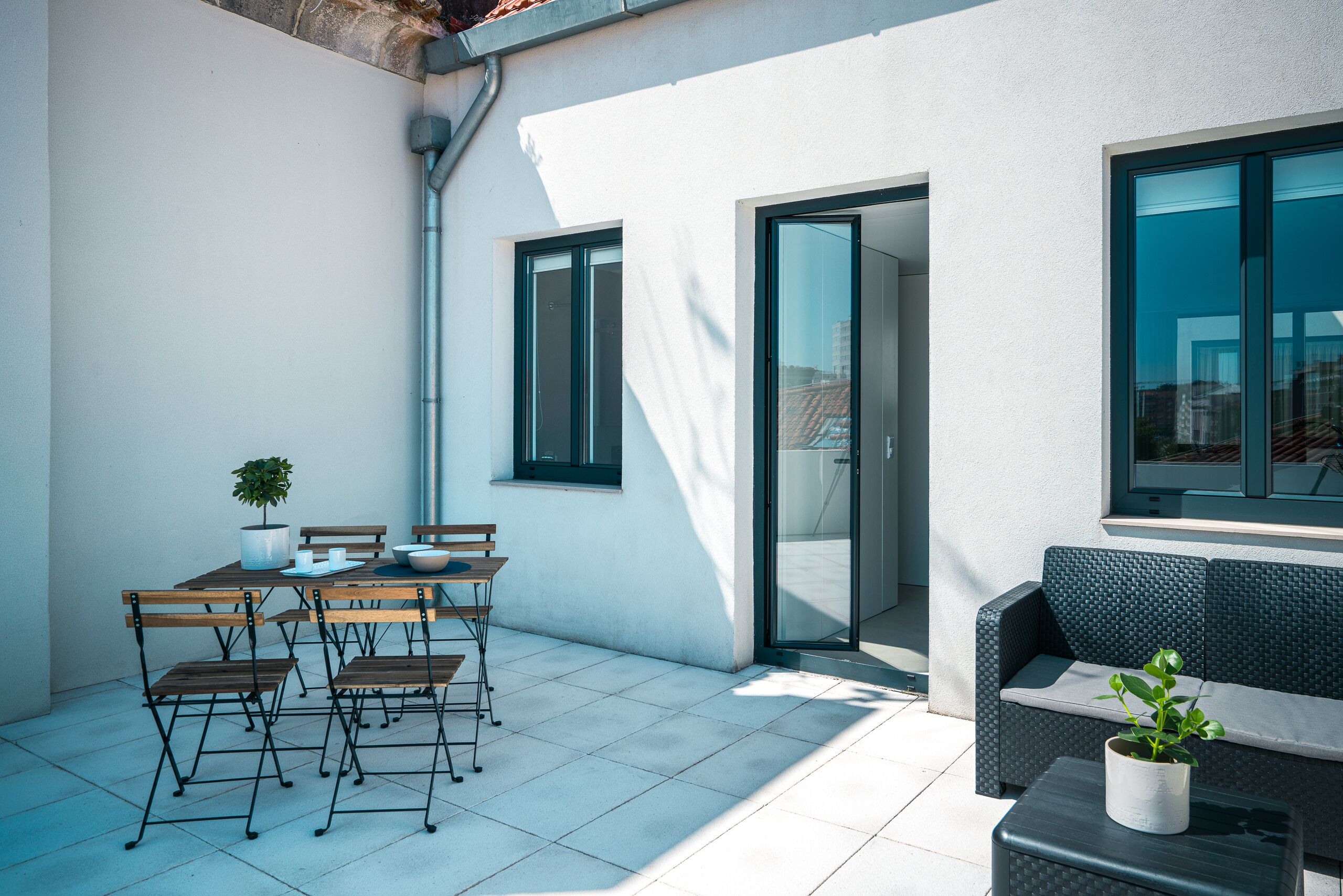 A patio with a table and chairs, a sofa, and a potted plant.