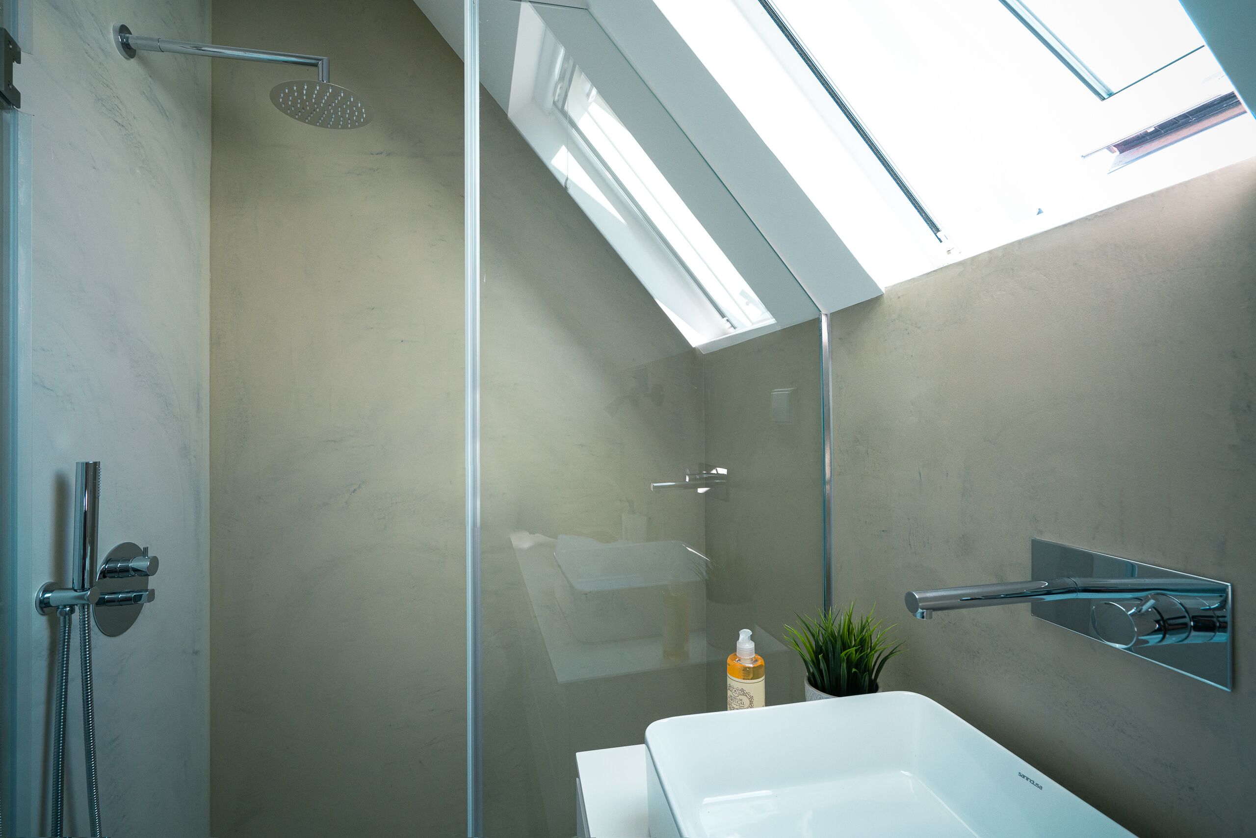 Een moderne badkamer met dakraam, douche, toilet en wastafel.