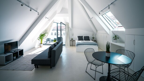A modern loft apartment with a high ceiling, skylights, a living area with a sofa and TV, a dining area with a table and chairs, and a bedroom with a bed and bedside tables. - Portaria Housing (Aveiro)