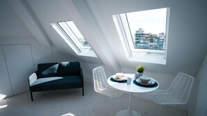A modern loft bedroom with skylights, a bed, a dining table with chairs, and a city view. - Portaria Housing (Aveiro)