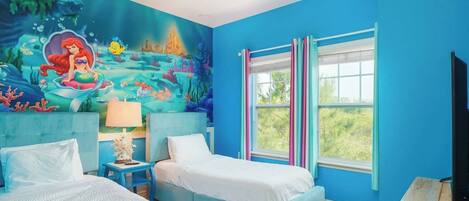 Un dormitorio con dos camas, un mural de una escena submarina y un amplio ventanal con cortinas.