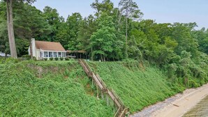 A coastal property with a wooden staircase leading down to a sandy beach. - Riverfront Cottage w/ Private Beach Near Wmsburg (Surry)