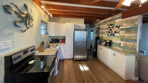 A kitchen with white cabinets, a stainless steel refrigerator, a microwave, and a stove. - Riverfront Cottage w/ Private Beach Near Wmsburg (Surry)