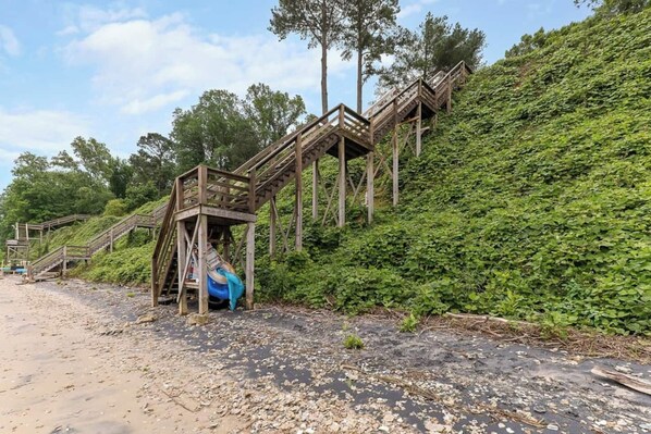 A wooden staircase leading up a hill with a blue kayak at the bottom.