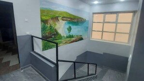A room with a mural of a landscape, a window, and a staircase. - Appartement F2 (Souk Tleta)