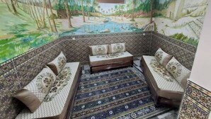 A room with a mural of a tropical landscape, a patterned floor, and a seating area with cushions. - Appartement F2 (Souk Tleta)
