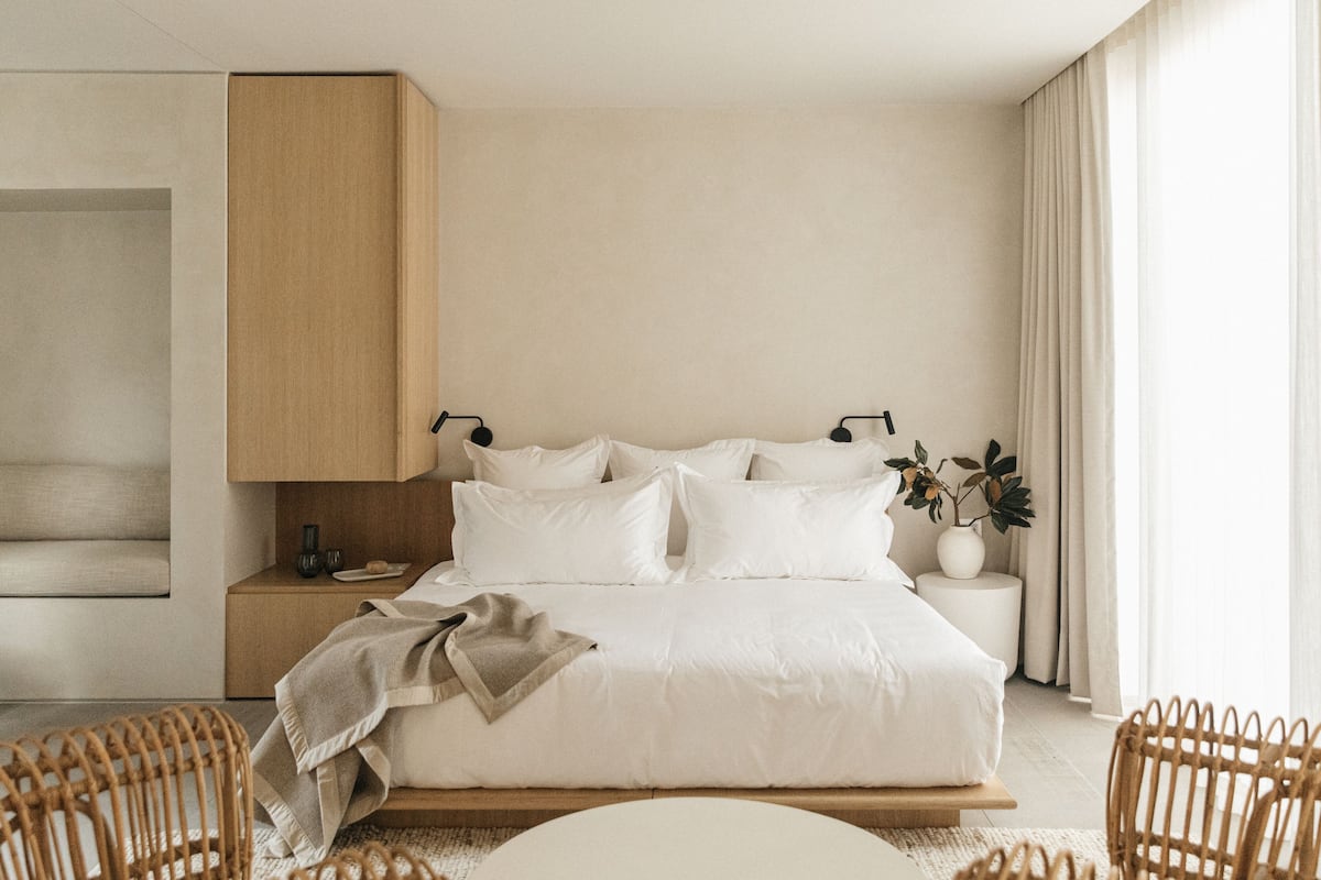A minimalist bedroom with a large bed, bedside tables, a wardrobe, and a window with curtains.