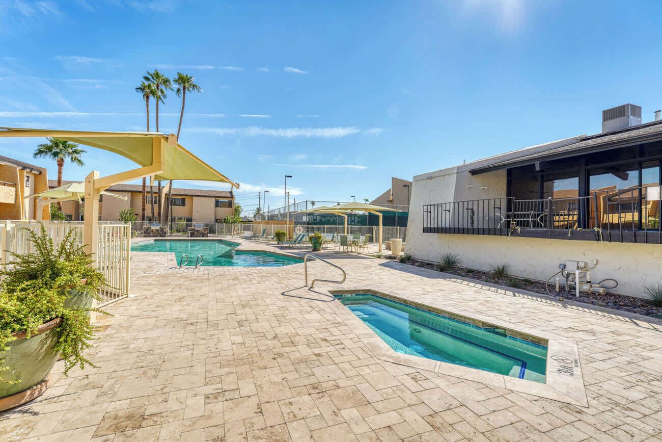 A pool area with two pools, palm trees, and a covered seating area.